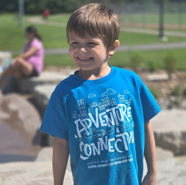 A boy wearing an Adventure Connection t-shirt.