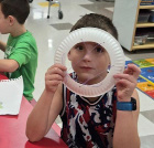 A child looking through a paper plate craft.