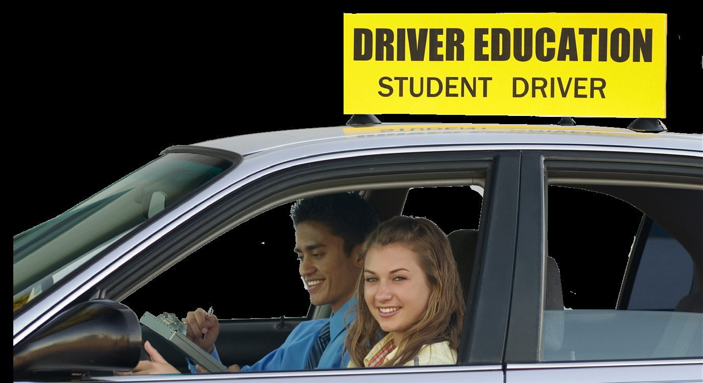 Two teenagers smiling while practicing driving in a car.