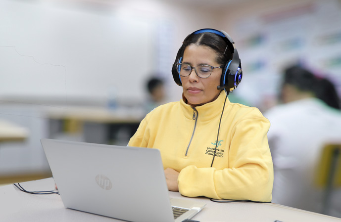 A student wearing headphones working on a laptop