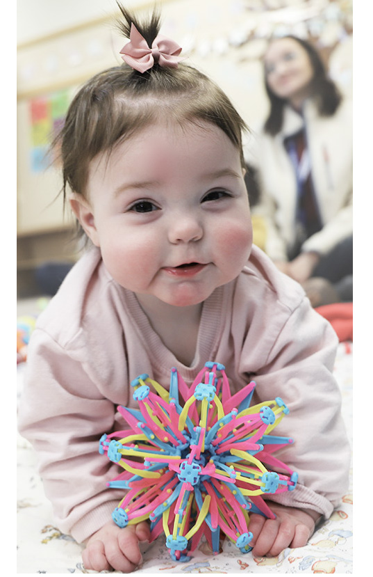 A smiling baby playing with a colorful toy