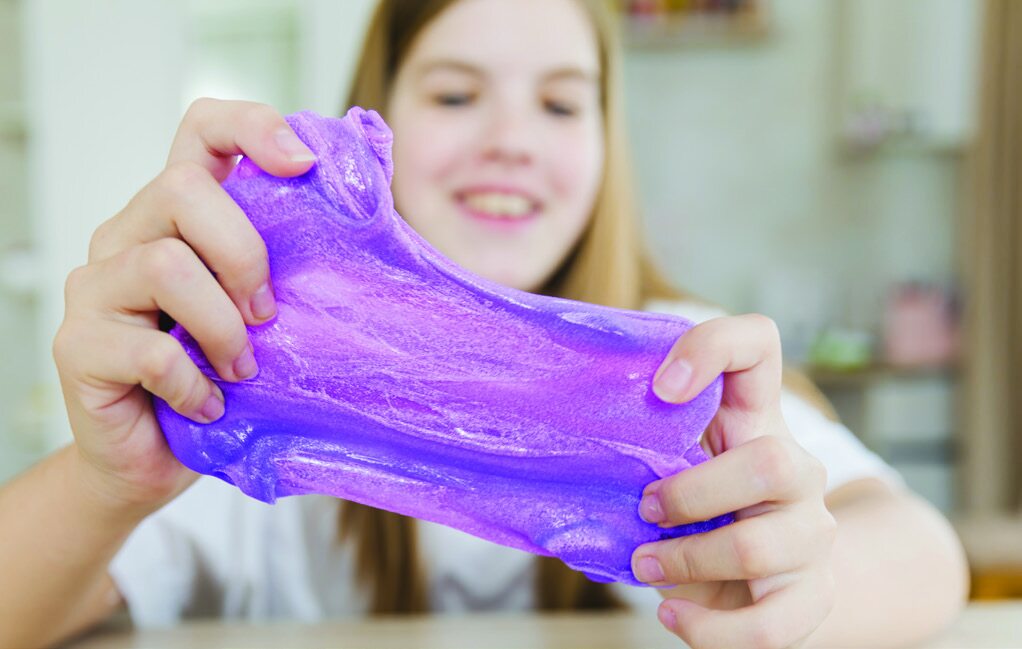 Child happily pulling and stretching purple slime