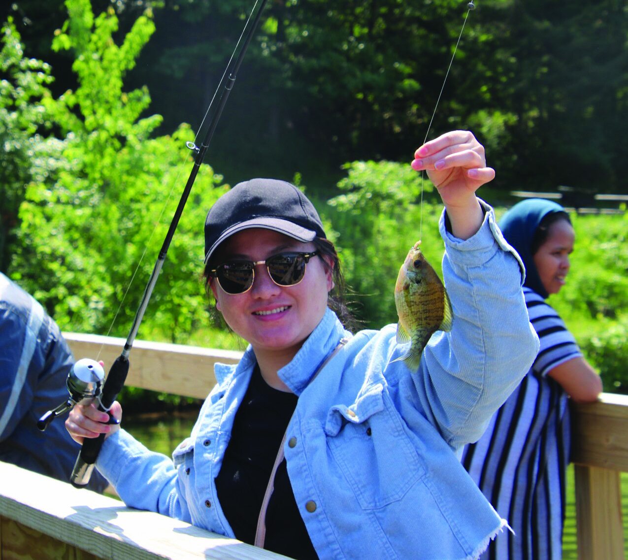 Woman smiling while holding up a small fish she caught