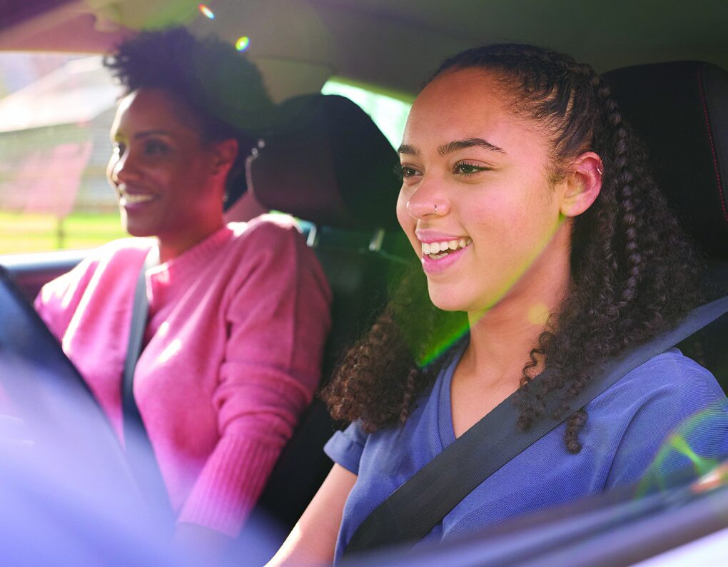 A smiling driving instructor and student inside a vehicle during a lesson
