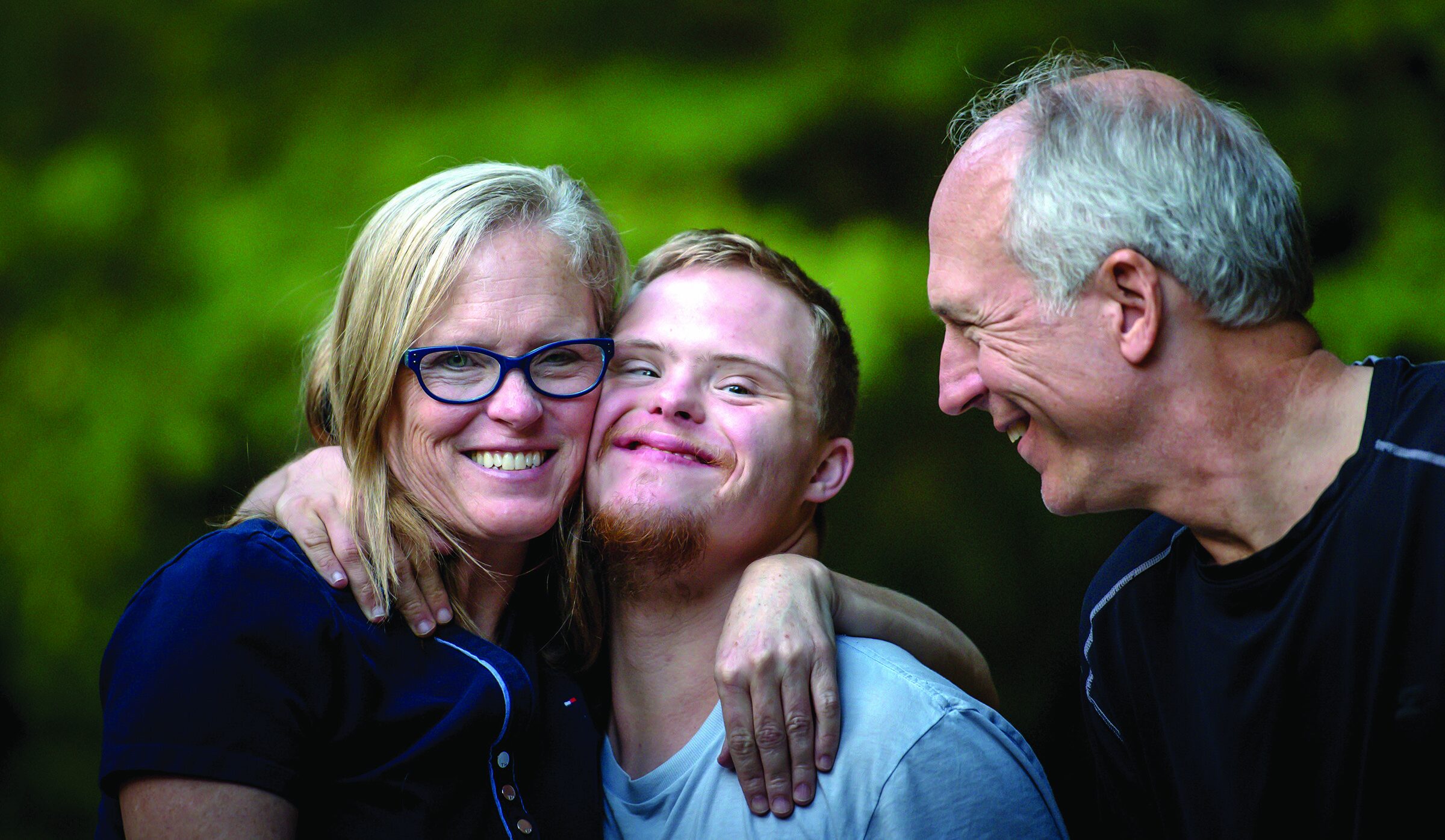A smiling woman with her arms around two men