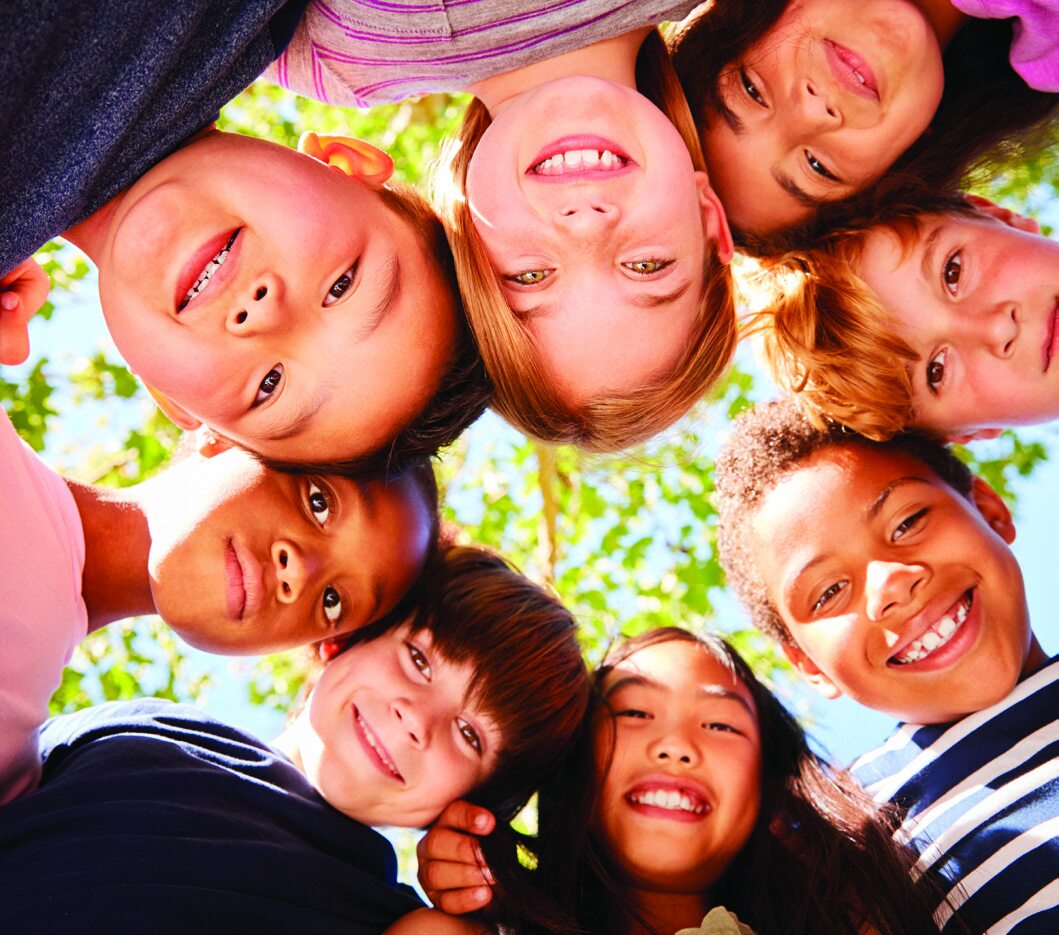 A group of diverse, smiling children looking down into the camera