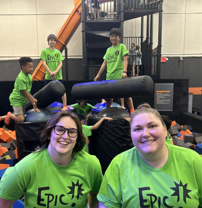A group of children and staff at an indoor activity center with trampolines and foam blocks.