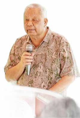 Gov. David M. Apatang speaking at a podium, wearing a patterned shirt