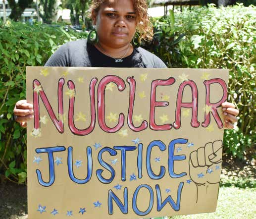 Person holding a 'NUCLEAR JUSTICE NOW' sign