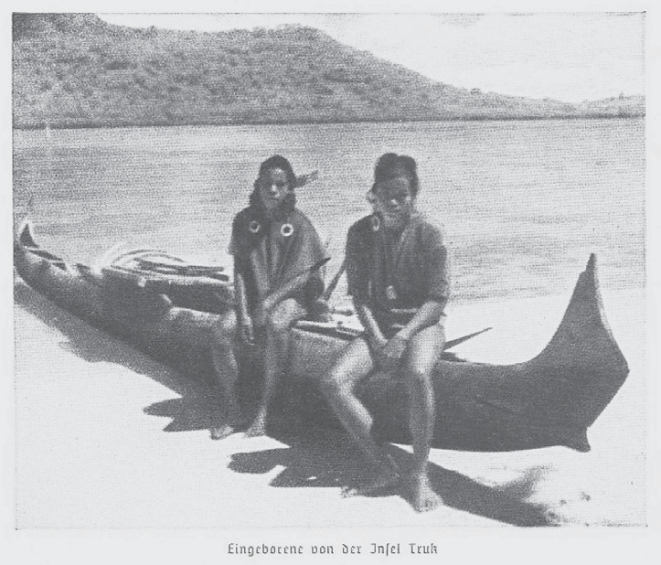 Archival photograph of two men in a canoe on a Micronesian beach
