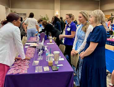 Photograph of vendor/attendees at the inaugural Levine JCC Women's Health Fair. Table with women in pink shirts and products on display.