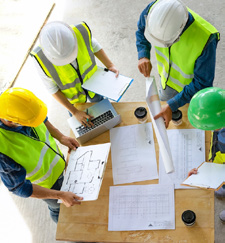 Construction professionals in safety gear reviewing architectural plans on a job site