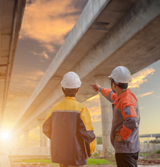 Two construction workers in safety gear discussing plans on site