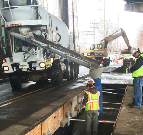 A concrete mixer truck pouring material into a utility trench on a construction site