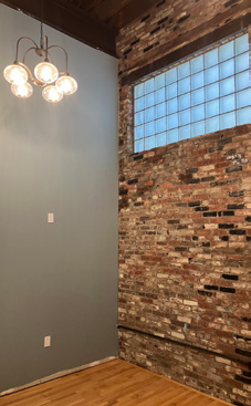 A room with an exposed brick wall and decorative hanging light fixtures.