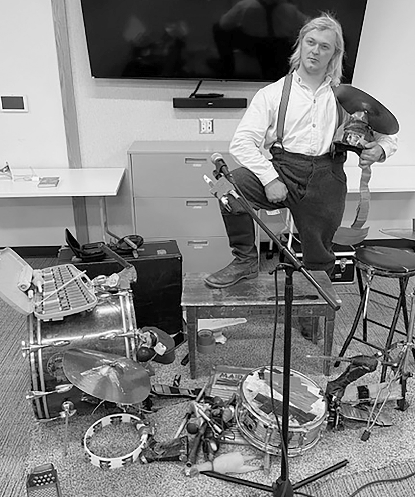 Steve Solkela, the 'Over-populated One-Man Band', seated with an accordion and an elaborate array of percussion instruments, bells, and a hockey helmet with attached cymbals.