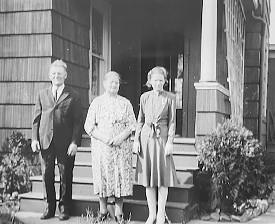 A black and white photograph from the Barberio family collection showing a man and two women standing on the front steps of Aunt Ina's house.