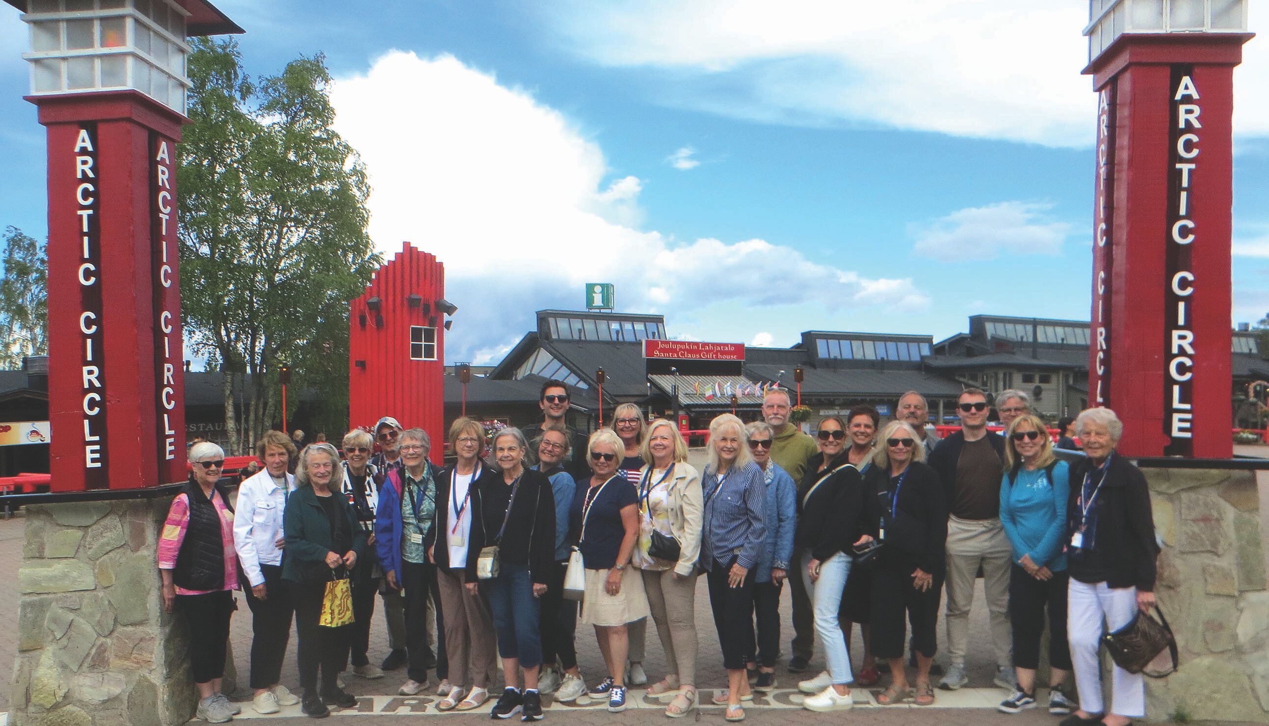 Smiley Group posed at the Arctic Circle between two red pillars, group photo