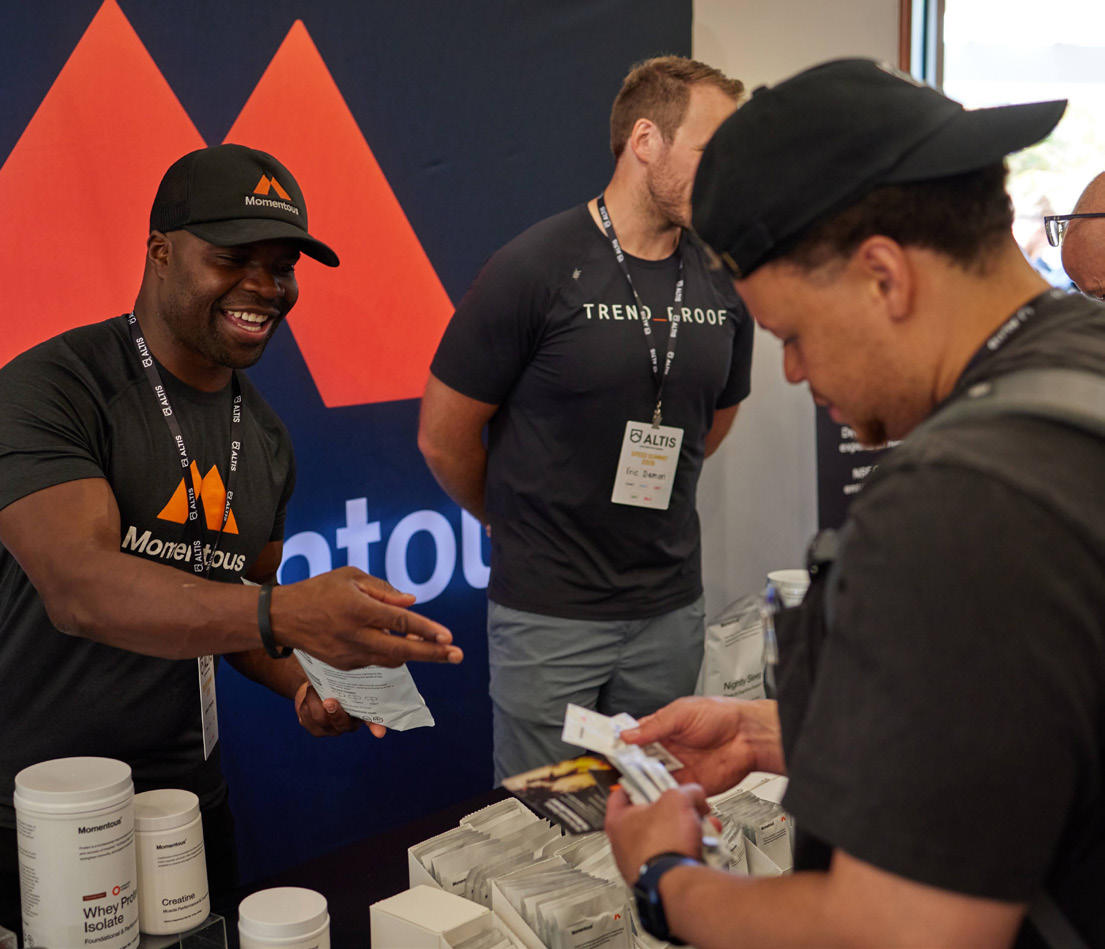A Momentous representative at a trade booth sharing samples
