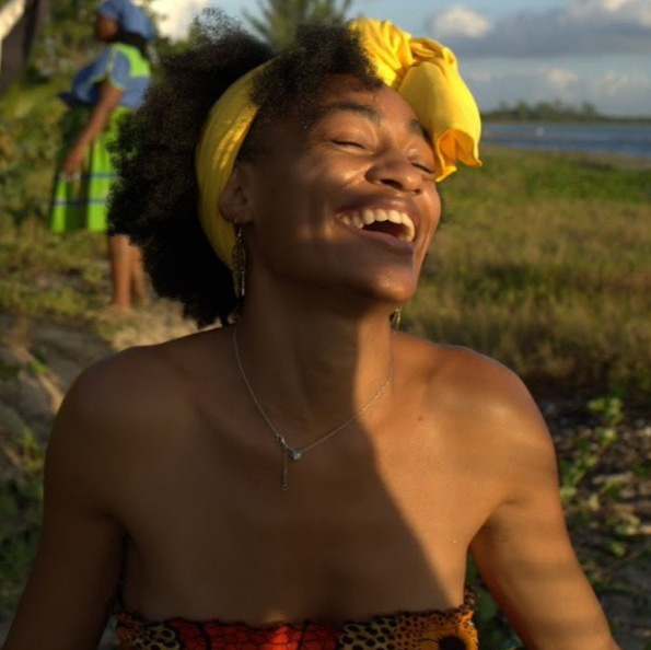 Khadeejah Clemons laughing outdoors, wearing a yellow headwrap