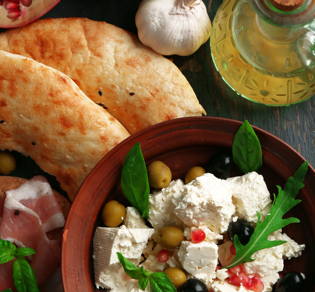 Mediterranean-style bowl with feta, olives, chickpeas and greens, with flatbreads and olive oil